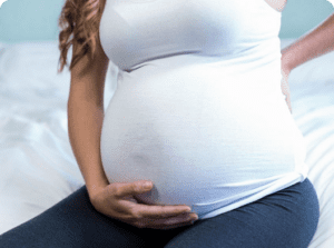 Conditions in pregnancy, a belly of a pregnat woman in a white shirt