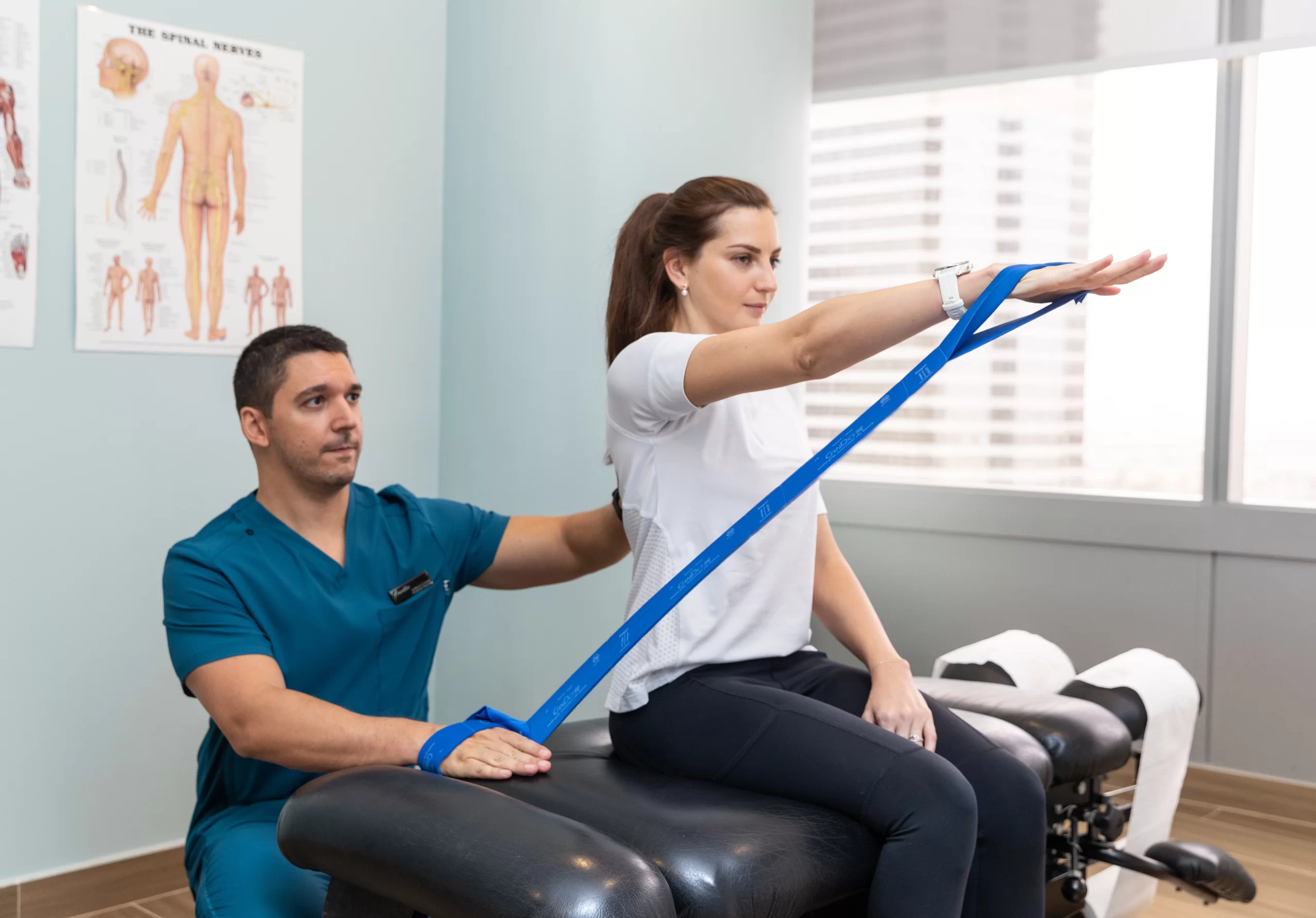 Physiotherapist at a leading physiotherapy clinic in Dubai assisting a female client with resistance band exercises for recovery and mobility.