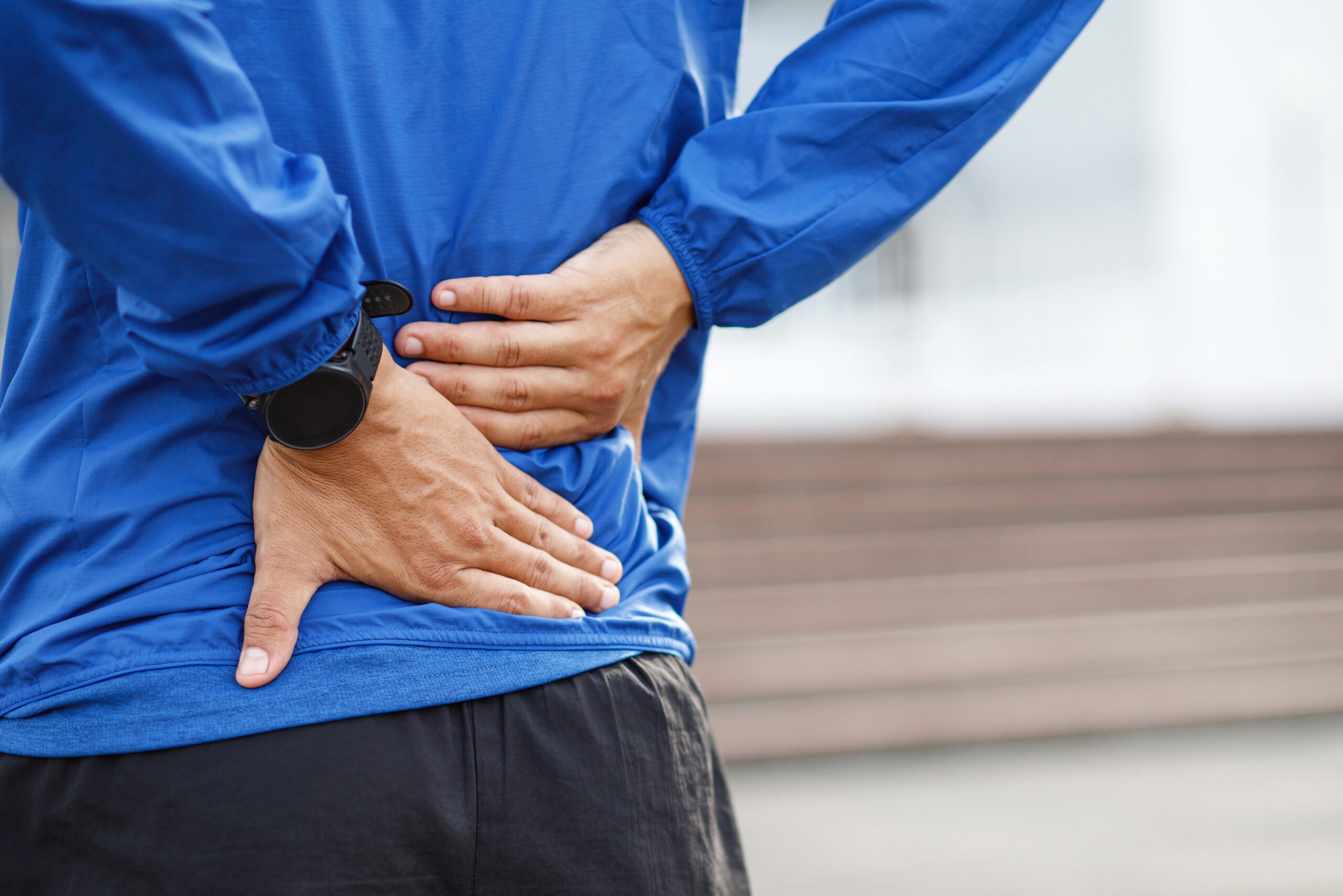 Person holding their lower back in pain while sitting at a desk in Dubai