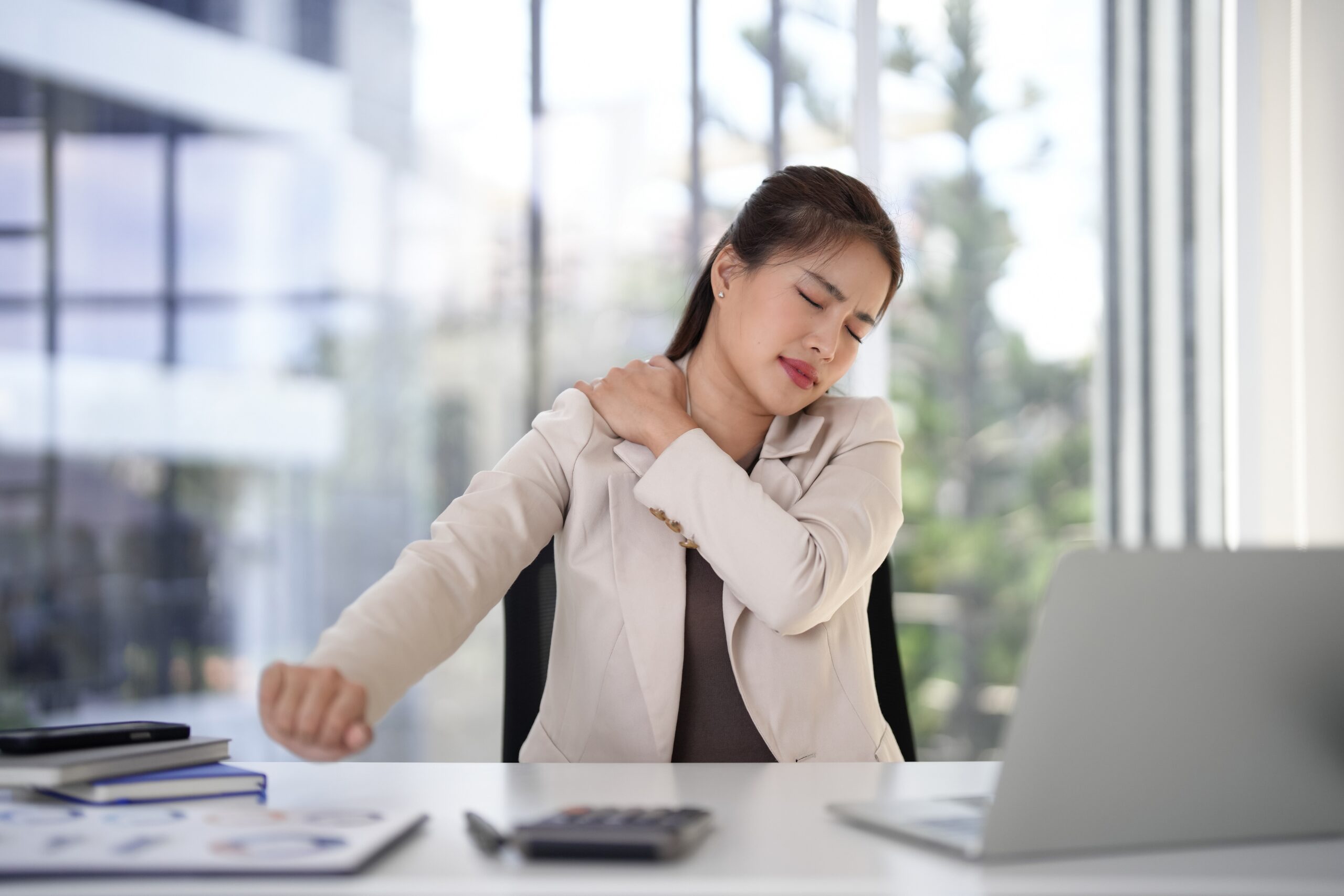 Office worker sitting at a desk holding a painful shoulder